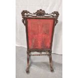 Victorian rosewood firescreen with a later floral fabric, with pierced scrolls, on scroll supports
