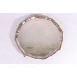 George V silver salver with pie crust edge, raised on four scroll feet by Fenton Brothers (