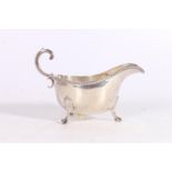 George V silver cream jug or sauceboat with feathered edge and double C-scroll handle by Horace