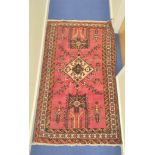 Persian wool rug with central diamond medallion on red field with cream, brown and orange borders,
