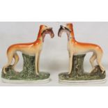 Pair of Staffordshire Pottery figures of greyhounds, each standing on naturalistic oval plinth base,