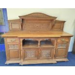 Late 19th century light oak sideboard, the arched raised back with dentil cornice and foliate carved