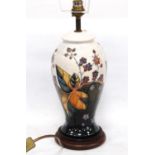 Moorcroft table lamp decorated with tube-lined flowers and leaves on a white ground, 28cm high.