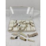 Collection of 19th century porcelain doll fragments in a segmented plastic case.