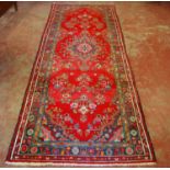 Persian hand-knotted rug decorated with all over floral medallions on a red and blue ground, 298cm x