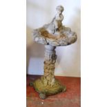 Stone garden bird bath decorated with a putti surmount to the open well, the cylindrical column with