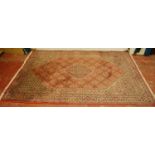 Keshan machine-made rug with a geometric medallion to the centre and all over floral motifs on a red