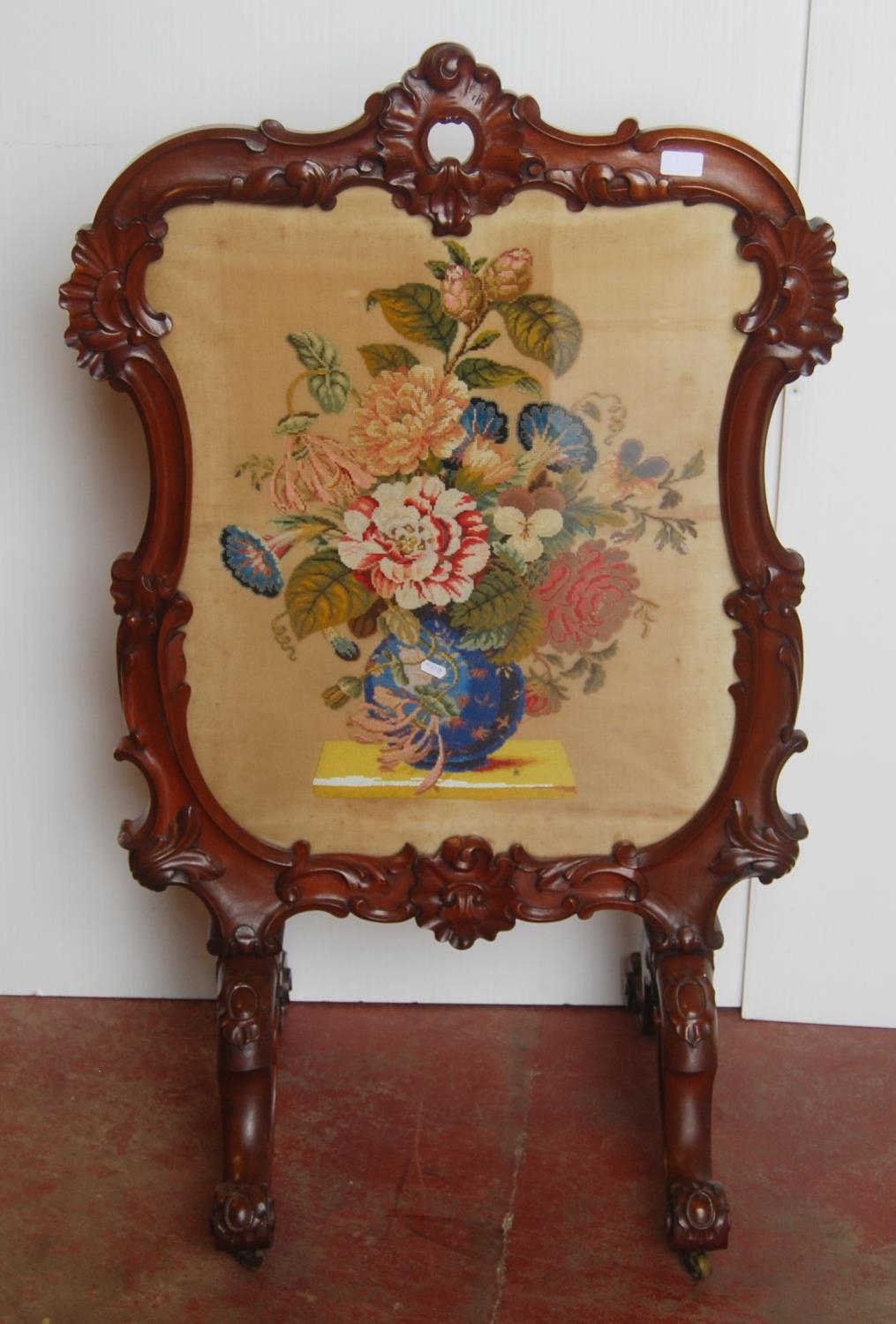 Victorian mahogany fire screen, with a needlepoint panel to the centre depicting flowers in a