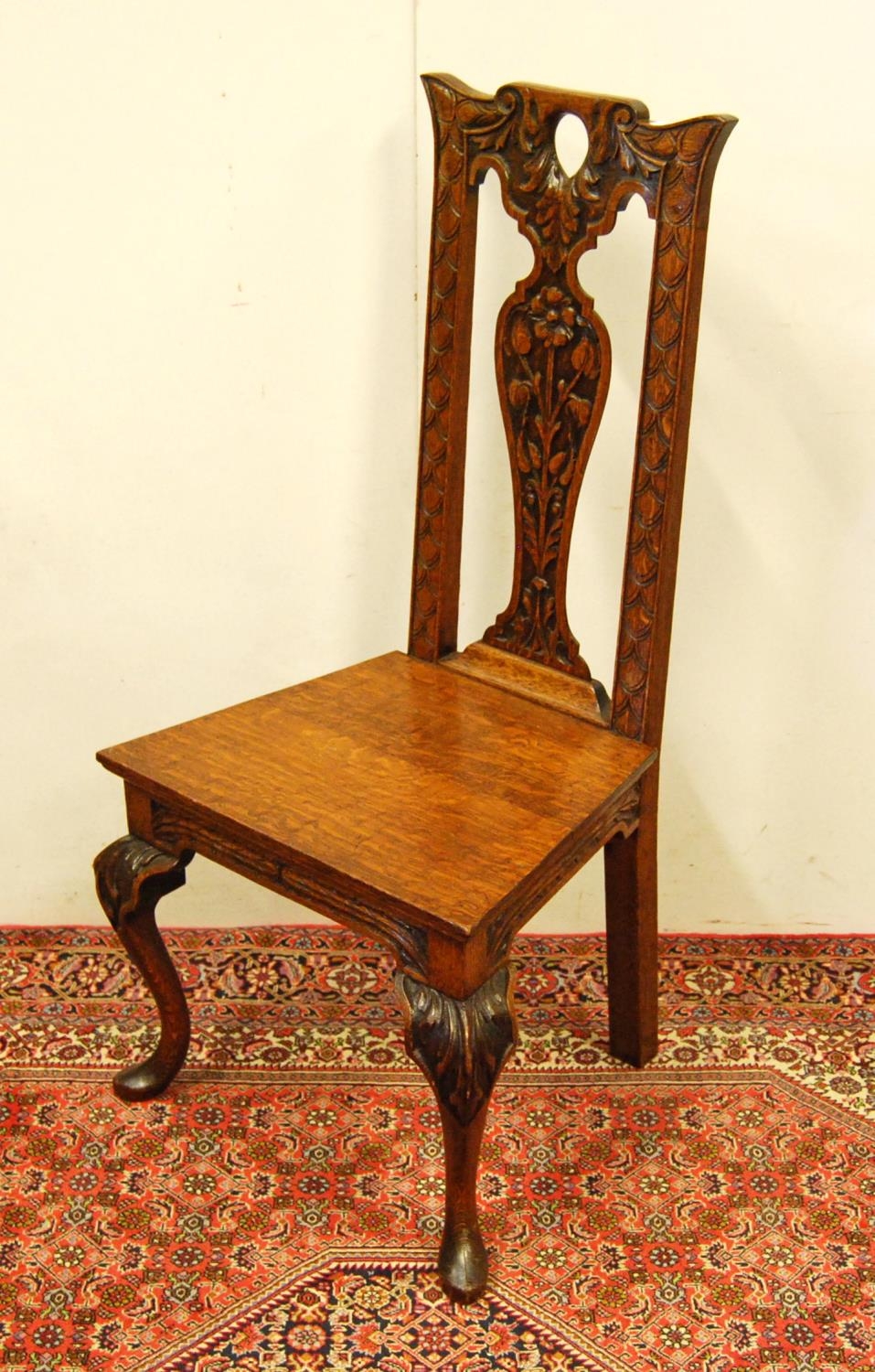 Early 20th century carved oak hall chair, the shaped top above a fiddle-shaped back rest carved with