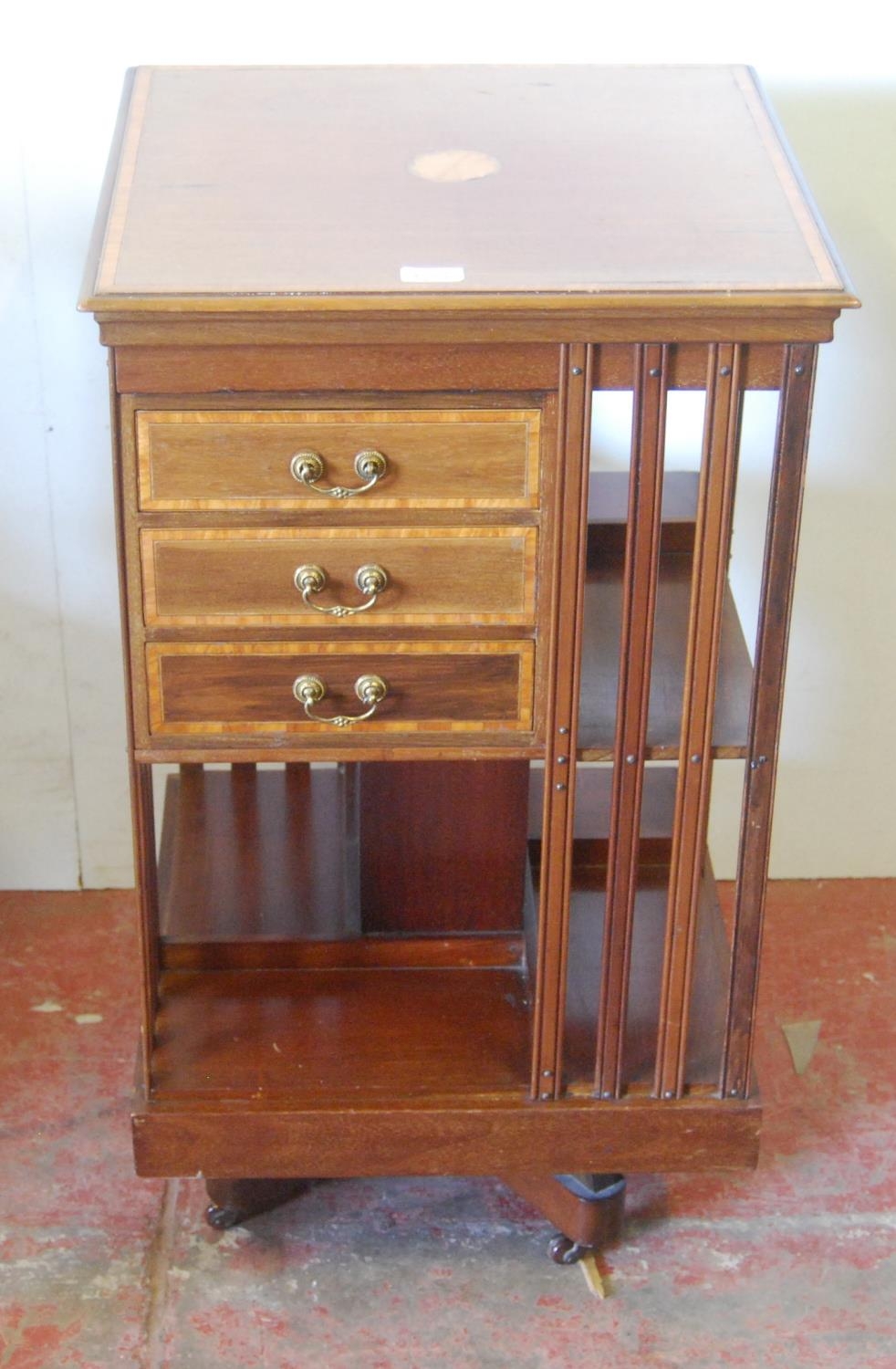 Edwardian inlaid mahogany revolving bookcase, with open shelving and three short drawers to the