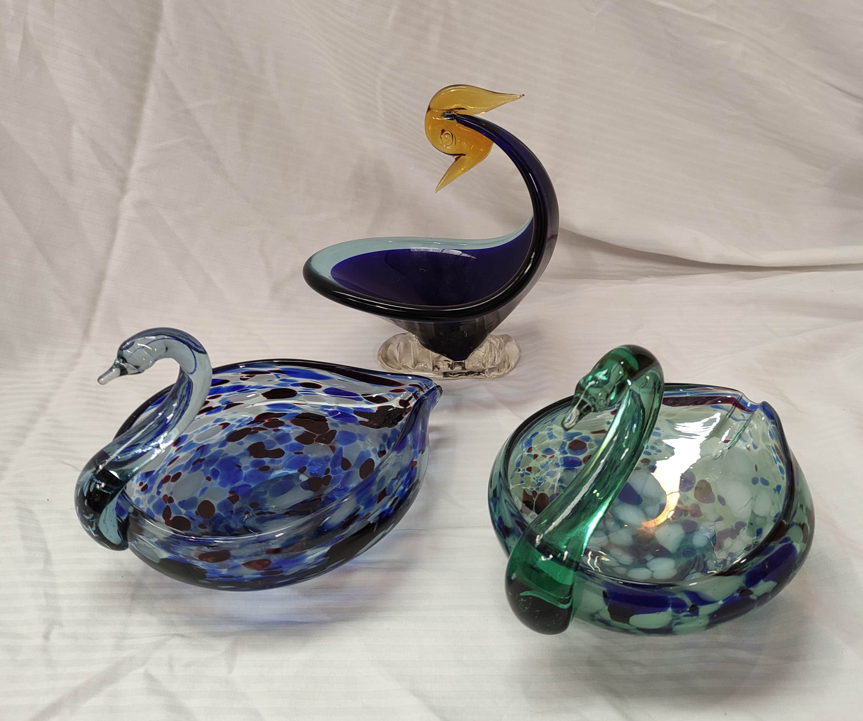 Two mottled art glass dishes in the form of swans, each 21cm long and another similar bird dish,