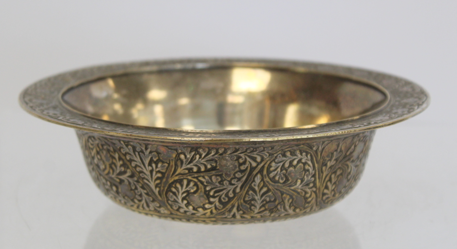 Oriental silvered circular brass bowl with engraved floral and foliate decoration, 16cm diam.