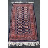 Bokhara hand-knotted rug on red and blue ground, 160cm x 93cm.