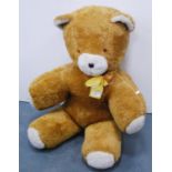 Large teddy bear with yellow ribbon.