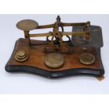 Set of antique brass postal scales with weights, on a walnut stand.
