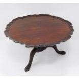 Mahogany revolving lazy susan with scalloped edge, on turned column and tripod ball and claw