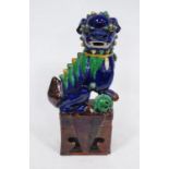 Chinese pottery temple guardian (Dog of Fo), glazed in brown, yellow and green on a blue ground,