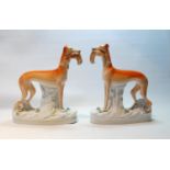 Pair of Staffordshire greyhound figures, each with prey in their mouths and fixed to shaped bases,