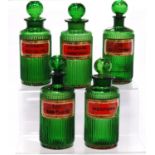 Five matching antique green glass chemist's jars with stoppers and ribbed decoration, named in black