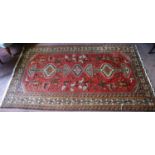 Persian rug decorated with all over geometric medallions and motifs on a red ground with cream