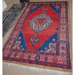 Dosemealti hand-knotted rug decorated with a large geometric medallion to the centre, on a red