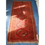 Bokhara rug decorated with six geometric medallions on a red ground, 170cm x 86cm.