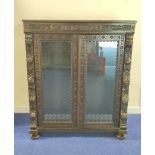 Victorian stained oak glazed bookcase with twin doors, carved with mask heads , fruit, flora and
