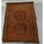 Afghan rug, the small antique hand knotted rug with two geometric medallions on rust ground, 100cm x