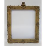 19th century gilt picture frame with floral and foliate scroll gesso moulding, the top surmounted by