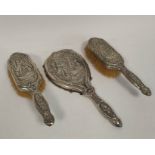 Silver hand mirror, embossed with a couple in a landscape with trees, and matching hair brushes,