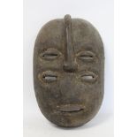 African tribal carved wooden mask of oval form with four pierced lidded eyes, central raised nose