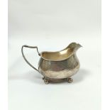 Silver cream jug of boat shape with engraved and pin struck decoration, on ball feet by Charles &