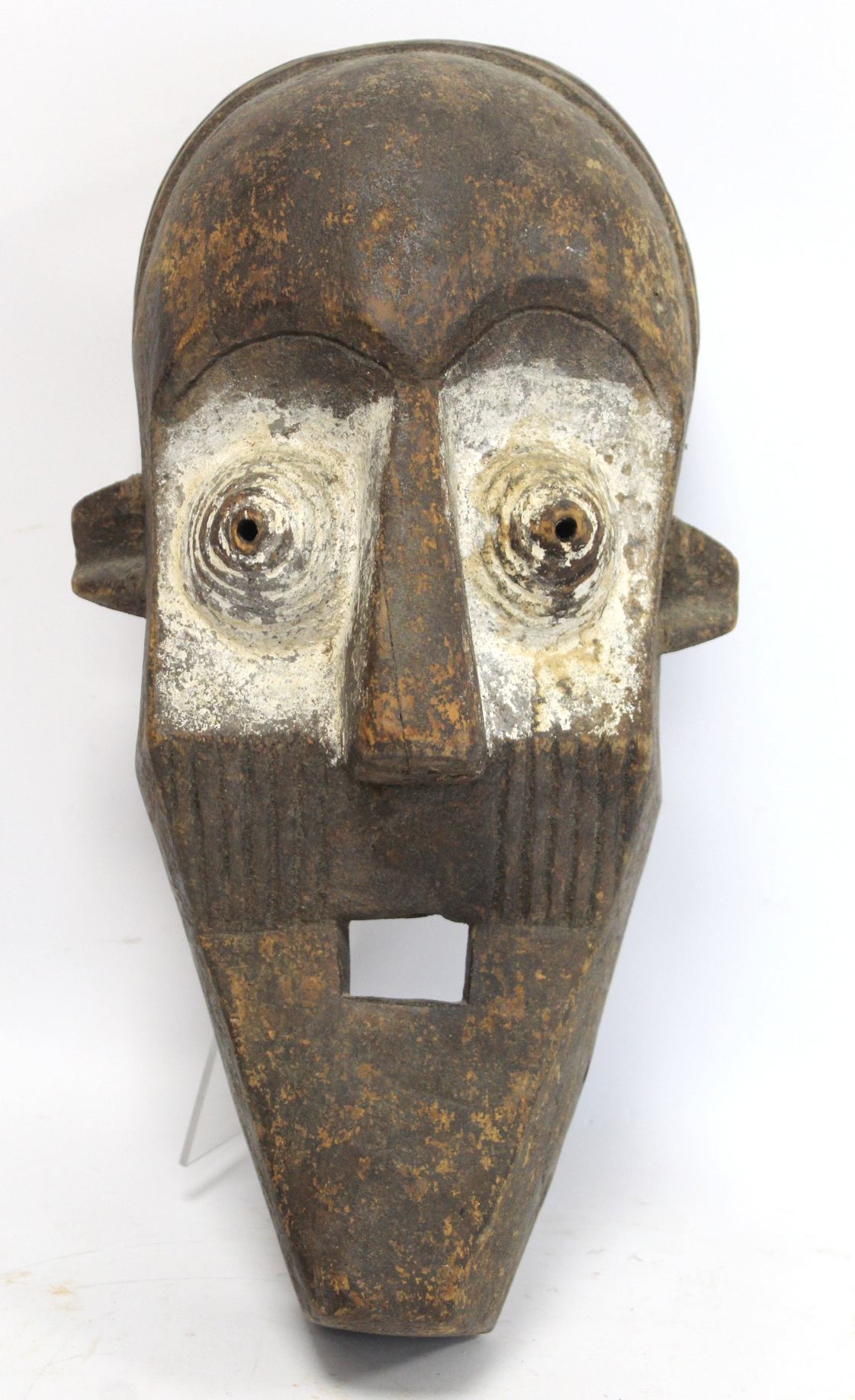 African tribal carved wooden mask of large elongated form with arched brow, conical ribbed eyes,