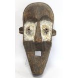 African tribal carved wooden mask of large elongated form with arched brow, conical ribbed eyes,