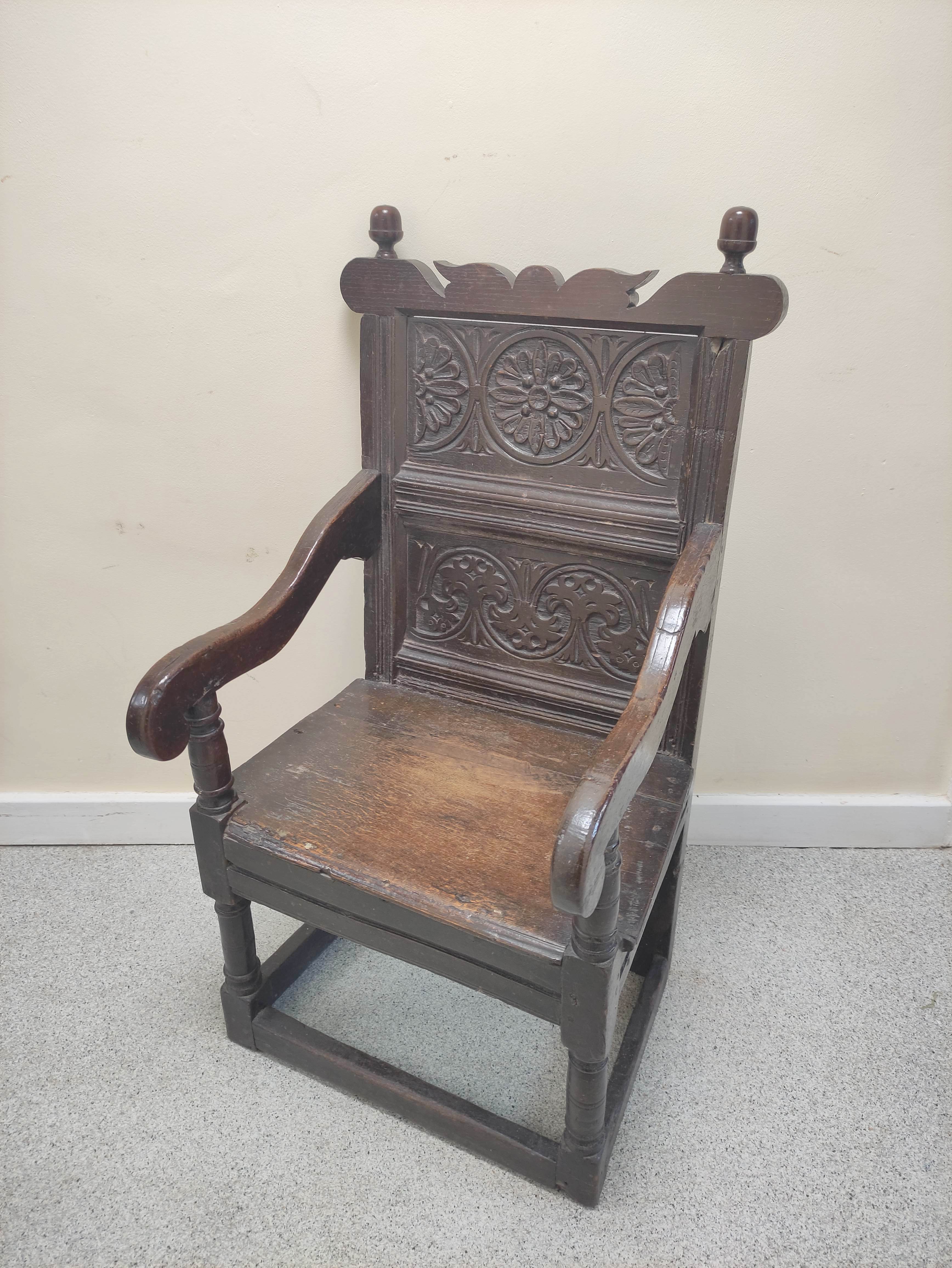17th century wainscot chair, the foliate carved panel back with acorn finials, above solid seat,