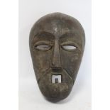 African tribal carved wooden mask with arched brows, elliptical lidded eyes, triangular nose and