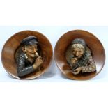 Pair of Continental pottery and treen wall plaques, depicting an elderly man with a pipe and