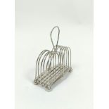 Rare silver folding toast rack, for six varying slices, with loop handle, the base stamped 'R C & Co