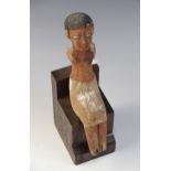 An Egyptian polychrome painted wood model figure, shown seated with arms missing, wearing a short