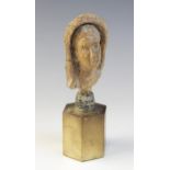 A limestone carved female head depicted wearing a himation partially covering her hair, set into