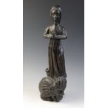 An oak carved figure of a maiden at prayer, standing upon a grotesque scaly creature, with mask