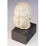 A carved marble head, depicting a young boy with distinctive hair details, 15m high, upon a plinth