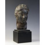 A carved stone female head, the dark coloured stone carving (possibly originally part of a larger