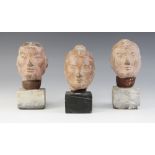 Three Chinese terracotta heads, possibly Han dynasty, each buff glazed exterior with moulded