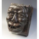 A late 15th century grotesque figural corbel, designed as a male smiling and bearing his teeth, 23.