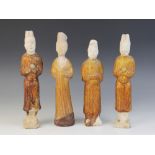 Four Chinese pottery amber glazed figures, possibly Tang dynasty, each modelled standing and with