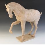 A large Chinese pottery model of a horse, possibly Tang dynasty, modelled on four legs, with one