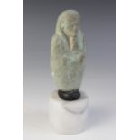 A fragmentary Egyptian blue glazed faience shabti, holding a pick and a hoe, worn bands of