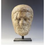 A worn marble male head carved with deeply furrowed brow, with restorations, 26cm high Provenance: