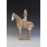 A Chinese pottery model of a figure riding a horse, possibly Tang dynasty, the horse raised on